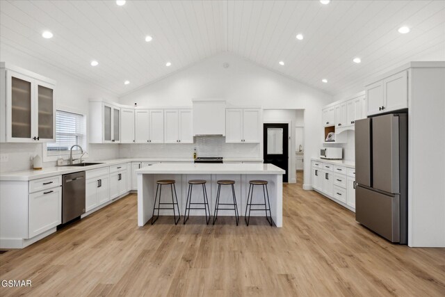 kitchen featuring white cabinets, backsplash, stainless steel appliances, and a kitchen island