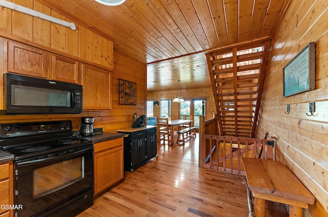 kitchen featuring dark countertops, brown cabinets, wood walls, and black appliances