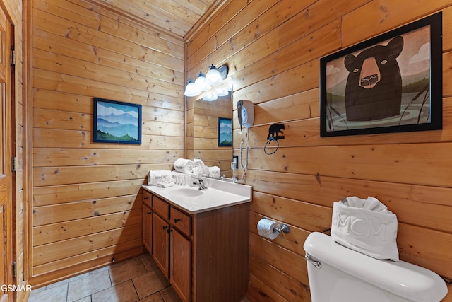 half bathroom with toilet, wood walls, vanity, and tile patterned floors