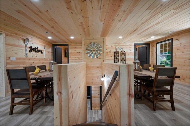 dining room with light wood-type flooring, wooden walls, and wood ceiling