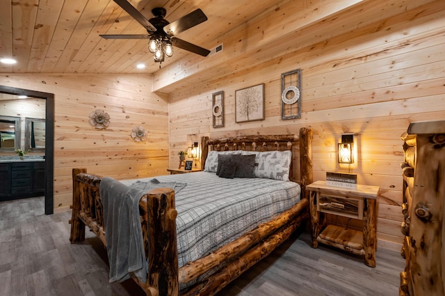 bedroom featuring ceiling fan, hardwood / wood-style floors, wood walls, and vaulted ceiling