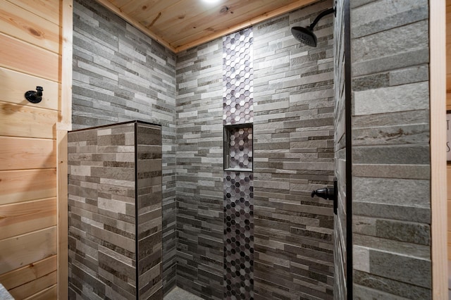 bathroom featuring a tile shower, wood walls, and wood ceiling