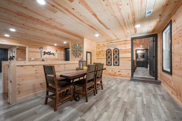 dining room with a skylight, wooden walls, hardwood / wood-style floors, and wooden ceiling