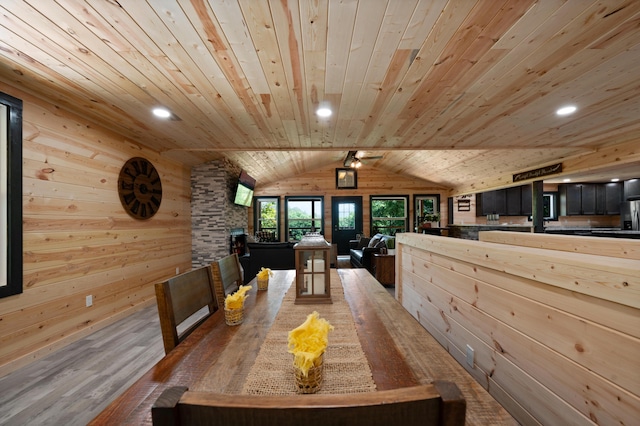 dining space with hardwood / wood-style flooring, lofted ceiling, wood ceiling, and wooden walls