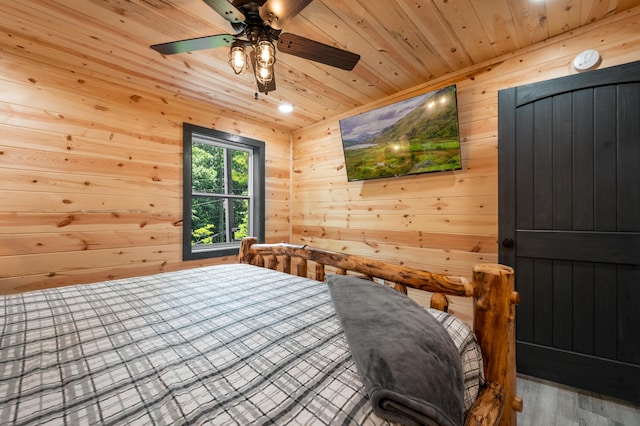 bedroom with ceiling fan, wood walls, and wooden ceiling