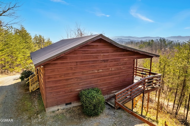 view of side of property with metal roof, crawl space, a mountain view, and a view of trees