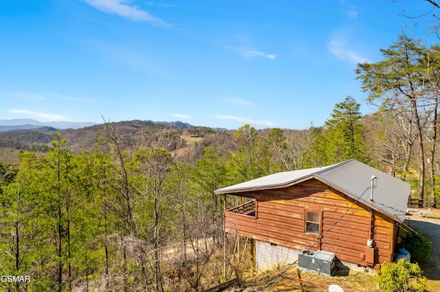 view of side of home with a forest view, a mountain view, and metal roof