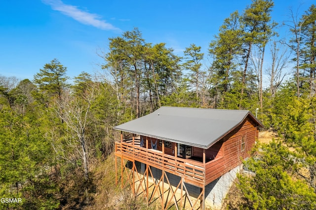 view of side of home featuring a forest view and metal roof