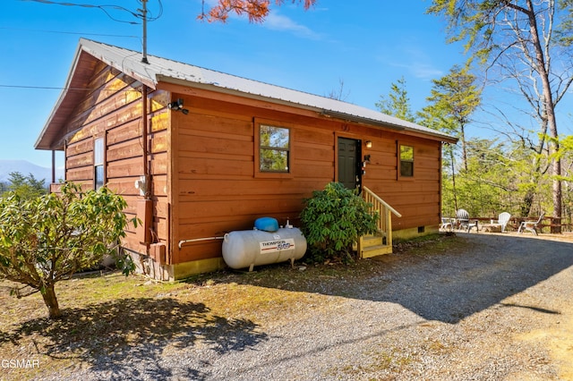 view of front of property featuring entry steps, metal roof, crawl space, and gravel driveway