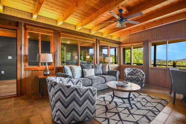 2837 Cedar Falls Way, Sevierville, TN 37862 - living area featuring wooden walls, beamed ceiling, wood ceiling, tile patterned floors, and a ceiling fan