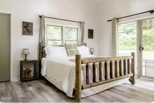 bedroom featuring access to outside, multiple windows, and hardwood / wood-style flooring