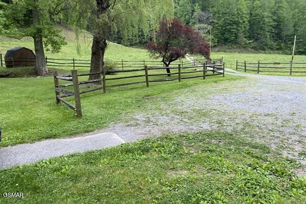 view of gate with a lawn and a rural view