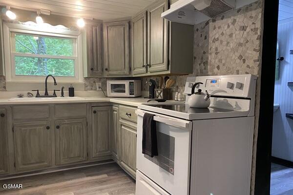 kitchen featuring white appliances, wooden ceiling, sink, wall chimney exhaust hood, and light hardwood / wood-style floors