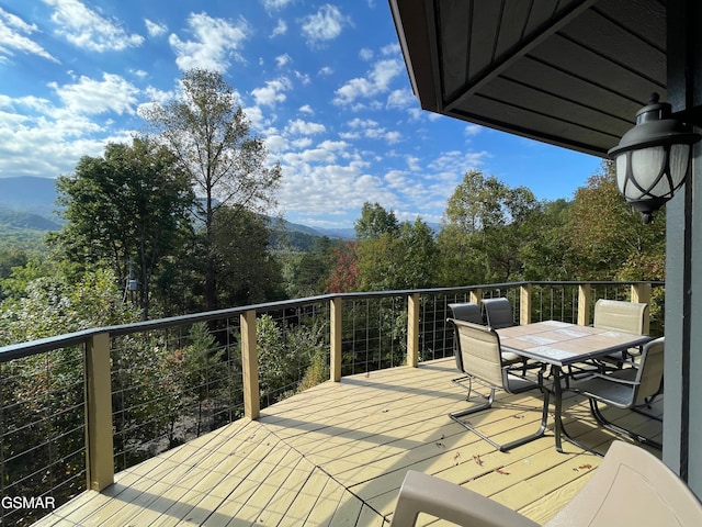 wooden deck with outdoor dining area and a mountain view