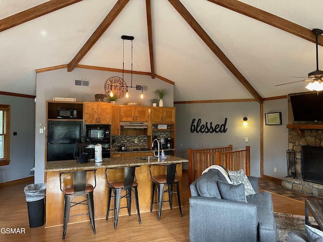 kitchen with pendant lighting, a breakfast bar area, decorative backsplash, and black appliances