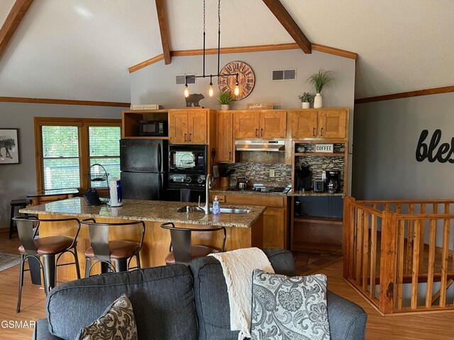 kitchen with pendant lighting, lofted ceiling with beams, decorative backsplash, light stone counters, and black appliances