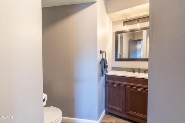 bathroom featuring baseboards, vanity, and toilet