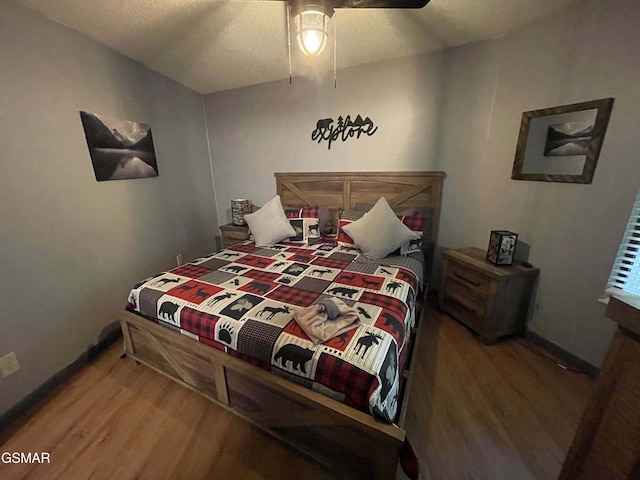 bedroom with ceiling fan, hardwood / wood-style floors, and a textured ceiling