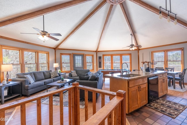 living area featuring ornamental molding, a wealth of natural light, vaulted ceiling with beams, and a textured ceiling