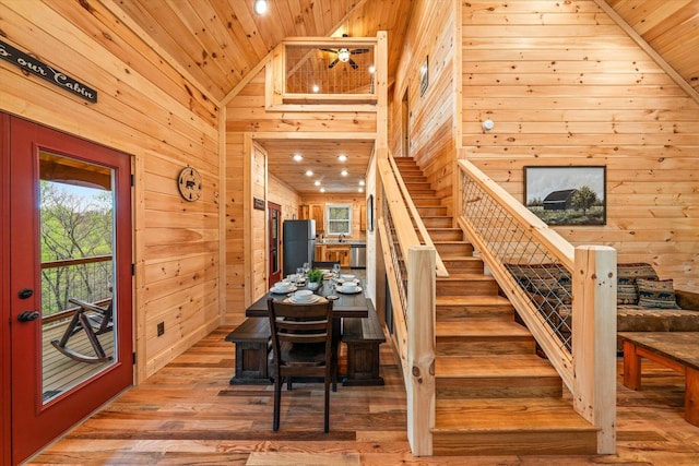 staircase featuring high vaulted ceiling, hardwood / wood-style floors, wood ceiling, and wooden walls