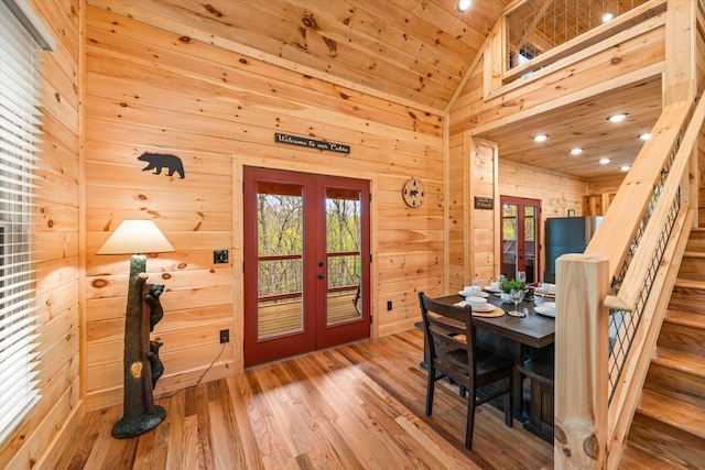 dining area with french doors, high vaulted ceiling, wooden ceiling, wooden walls, and hardwood / wood-style floors