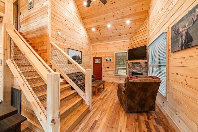 interior space featuring a fireplace, high vaulted ceiling, wood-type flooring, and wood walls