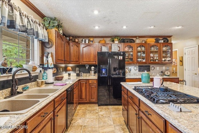 kitchen with light stone countertops, sink, a textured ceiling, black appliances, and ornamental molding