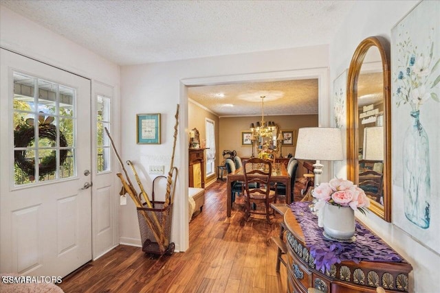 entrance foyer featuring dark hardwood / wood-style flooring, a textured ceiling, and a notable chandelier