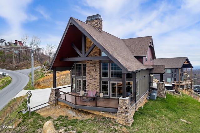 710 Wiley Oakley Dr, Gatlinburg, TN 37738 - back of property featuring roof with shingles, stone siding, a chimney, a wooden deck, and a lawn