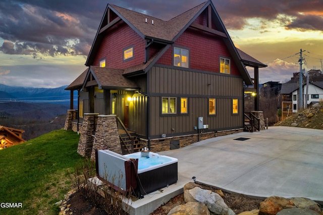 710 Wiley Oakley Dr, Gatlinburg, TN 37738 - back of house featuring board and batten siding, a hot tub, a shingled roof, a mountain view, and a yard