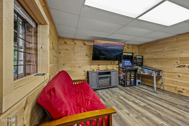 interior space with hardwood / wood-style floors, a drop ceiling, and wood walls