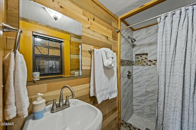 bathroom featuring a textured ceiling, wood walls, sink, and curtained shower