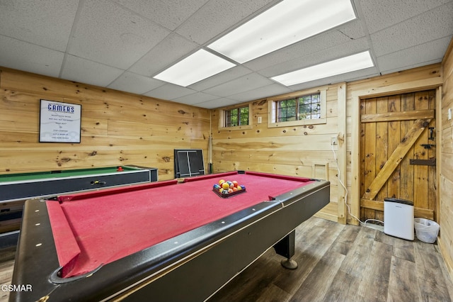 rec room featuring hardwood / wood-style flooring, a drop ceiling, wood walls, and pool table