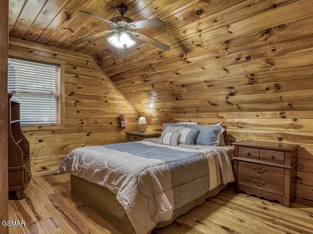 bedroom with light wood-style flooring, lofted ceiling, wood walls, and wooden ceiling