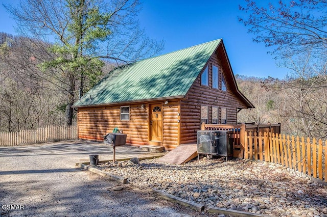 exterior space with metal roof, driveway, and fence