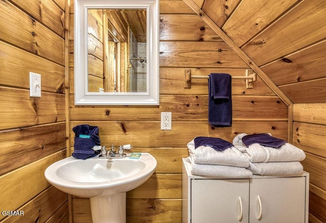 bathroom featuring wooden walls and a sink