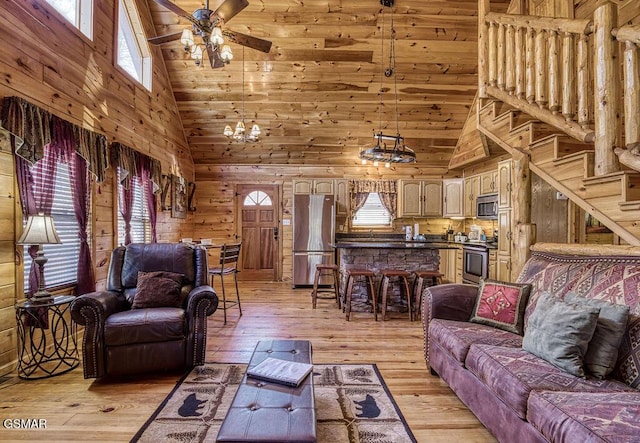 living area with wooden walls, light wood-style flooring, lofted ceiling, and a ceiling fan