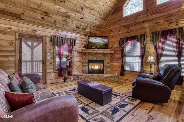 living room featuring hardwood / wood-style floors, a stone fireplace, wood walls, and wooden ceiling