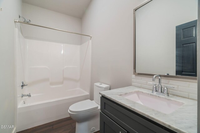 full bath featuring decorative backsplash, toilet, wood finished floors, bathing tub / shower combination, and vanity