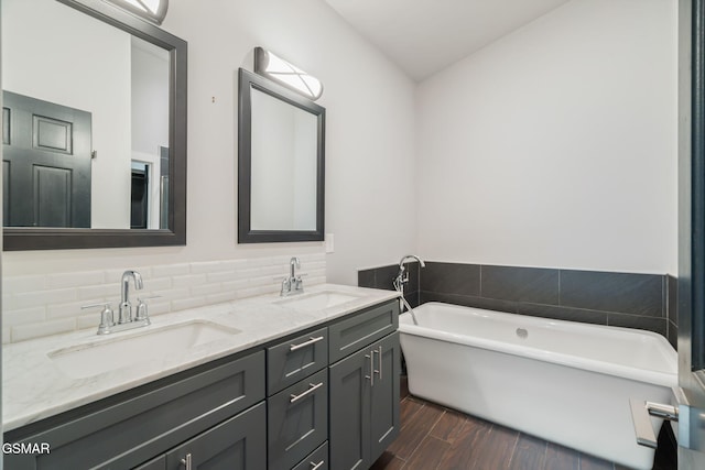 bathroom with a freestanding tub, double vanity, and wood finished floors