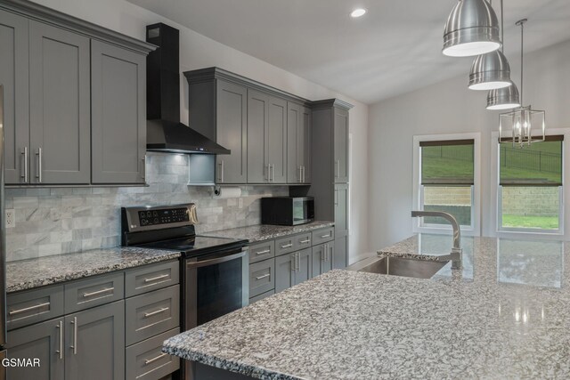 kitchen with wall chimney exhaust hood, a sink, appliances with stainless steel finishes, backsplash, and lofted ceiling
