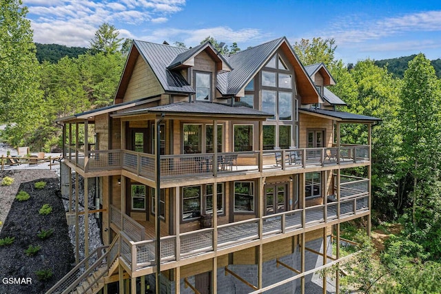 rear view of property with a standing seam roof, metal roof, and a wooded view