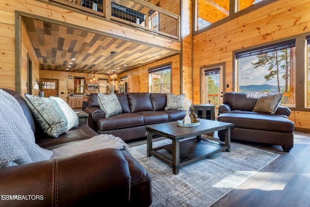 living room featuring a towering ceiling, wooden walls, and wood finished floors