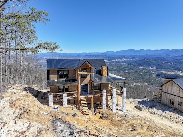 view of front of home with a chimney, stairs, a mountain view, and metal roof