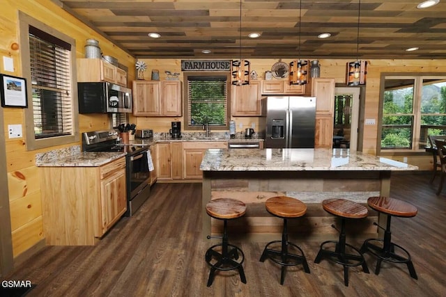 kitchen with dark wood finished floors, stainless steel appliances, light brown cabinetry, a sink, and a kitchen breakfast bar