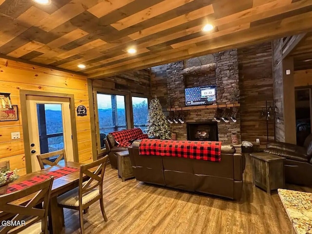 living room featuring wooden ceiling, wood walls, wood finished floors, and a stone fireplace