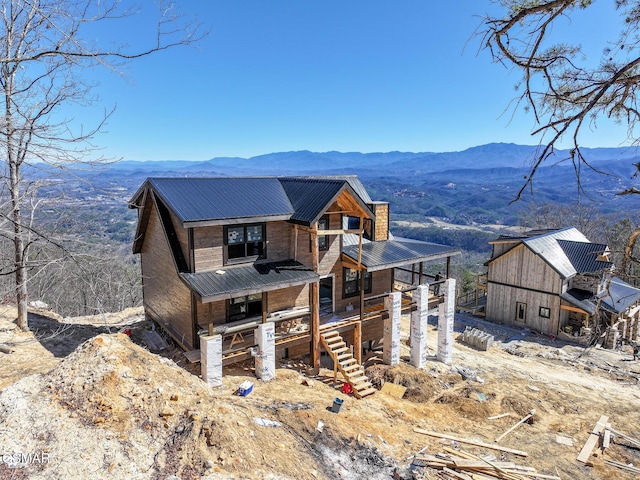 view of front of house featuring a chimney, stairway, metal roof, a mountain view, and a porch