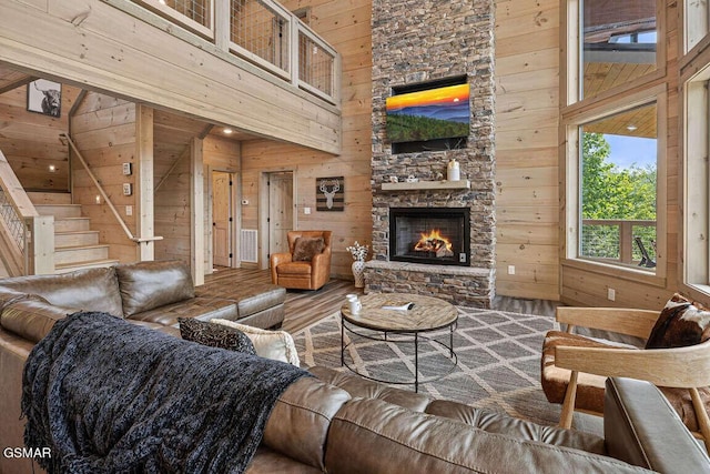 living area with a towering ceiling, wood walls, and wood finished floors