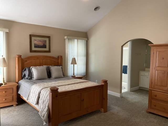 carpeted bedroom featuring connected bathroom and vaulted ceiling