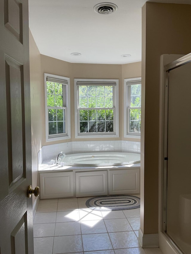 bathroom with tile patterned flooring, separate shower and tub, and a healthy amount of sunlight